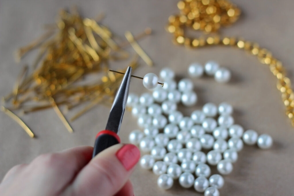 Girl's hands making a necklace with white beads