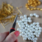 Girl's hands making a necklace with white beads