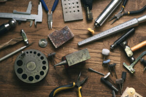 Top view jewelry maker workbench with tools on table. Equipment and tools of a goldsmith on wooden working desk inside a workshop.