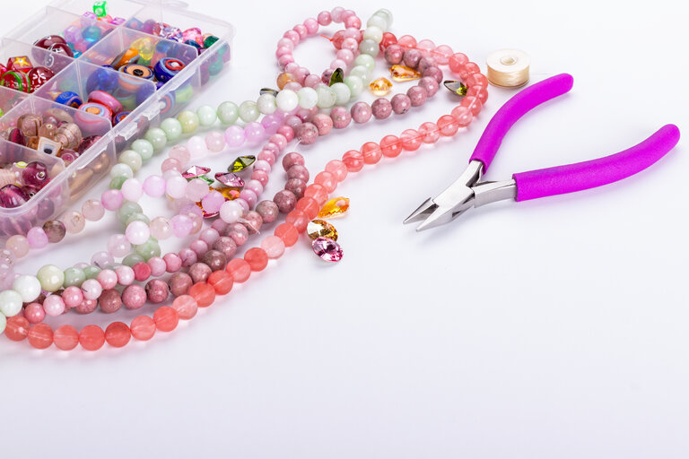Rose quartz beads for beadwork on white background. Hobby, handmade, fine arts. Selective focus